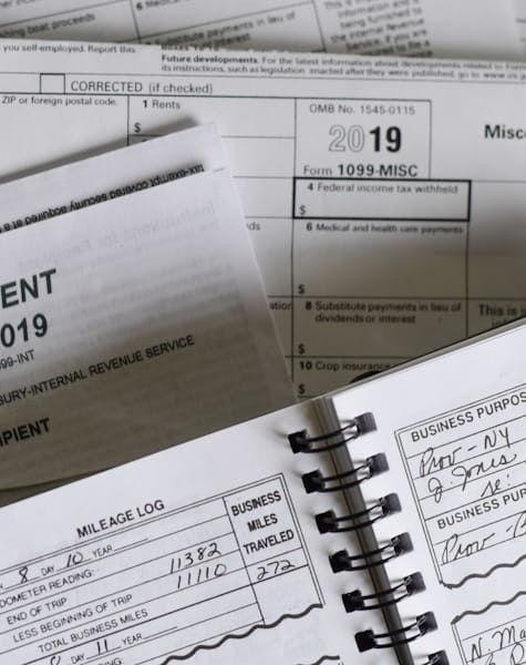Formularios fiscales anuales junto a un registro de gastos deducibles