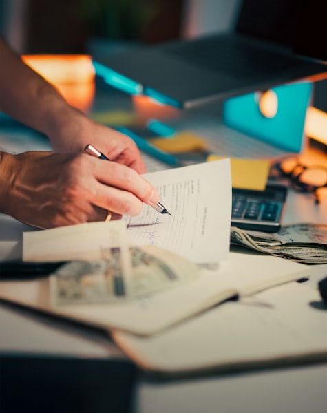 Persona firmando documentos fiscales en un escritorio de oficina