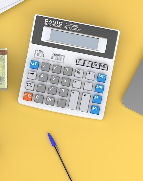 Calculadora de oficina sobre fondo amarillo junto a un bolígrafo