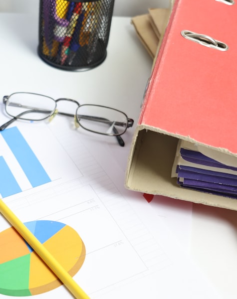 Carpeta de archivos, gafas y gráficos financieros sobre un escritorio