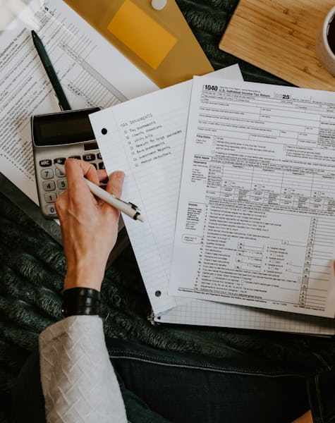 Persona revisando formularios contables con calculadora y bolígrafo