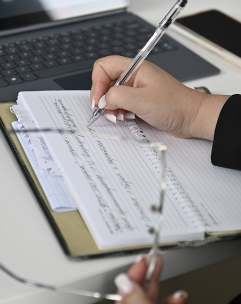 Manos anotando cifras en un libro de registros contables